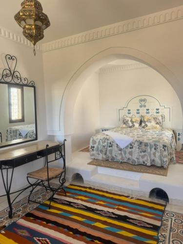 a bedroom with a bed and a mirror and a rug at Dar amiratt in El Guecheïne