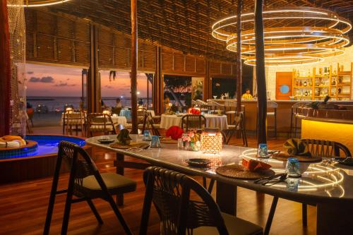 a dining room with a table and chairs and the ocean at Furaveri Maldives - COMPLIMENTARY ROUND-TRIP SEAPLANE TRANSFER FOR TWO FOR A MINIMUM OF 5 NIGHTS OR MORE FOR STAYS 1ST MAY 2026 TO 23RD DECEMBER 2026 in Raa Atoll