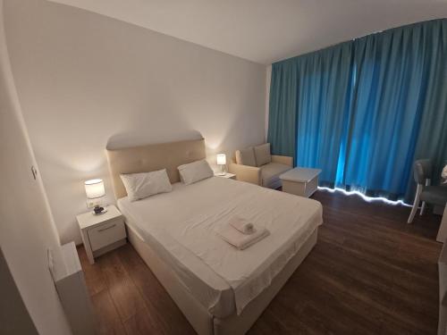 a bedroom with a white bed and blue curtains at Blue Sea OLIMP by Any - Etaj PREMIUM cu vedere la Mare in Olimp