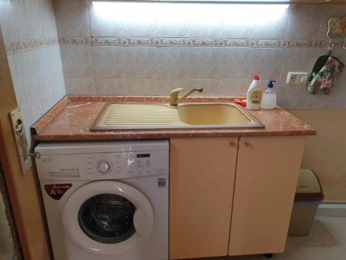 a kitchen counter with a sink and a washing machine at The Blacksmith's Guesthouse in Shkodër