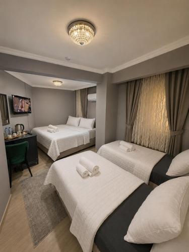 a hotel room with three beds and a table at Çorlu Aras Hotel & City Center Location in Çorlu