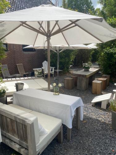 a table and chairs with an umbrella and benches at The Beach House in Schellinkhout
