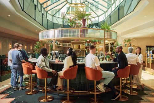 a group of people sitting at a bar in a restaurant at Van der Valk Hotel Park Lane Antwerpen in Antwerp