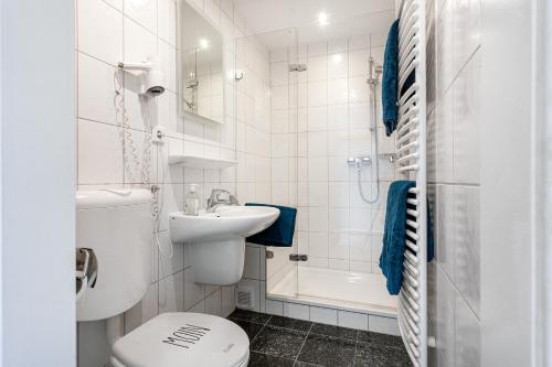 a white bathroom with a toilet and a sink at Bungalow Windsbraut in Norddeich