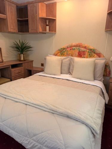 a bedroom with a large white bed with a wooden headboard at Swans Rest - Lakeside Caravan Park in Denver