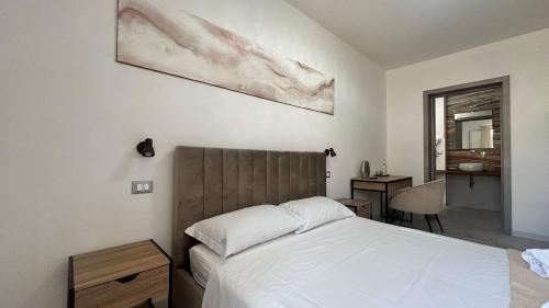 ein Schlafzimmer mit einem weißen Bett und einem Schreibtisch mit Spiegel in der Unterkunft Yllen Rooms in Avola