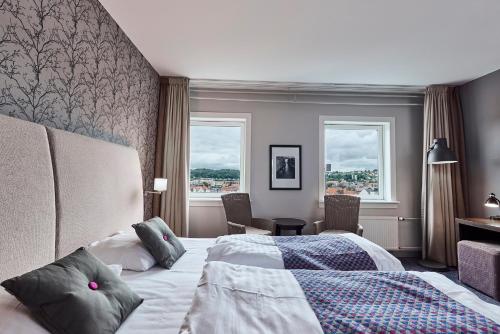 a hotel room with a bed and a desk and two windows at Hotel Cabinn Vejle in Vejle