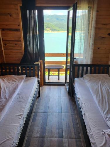 two beds in a room with a view of a lake at Vila Arena in Mandići