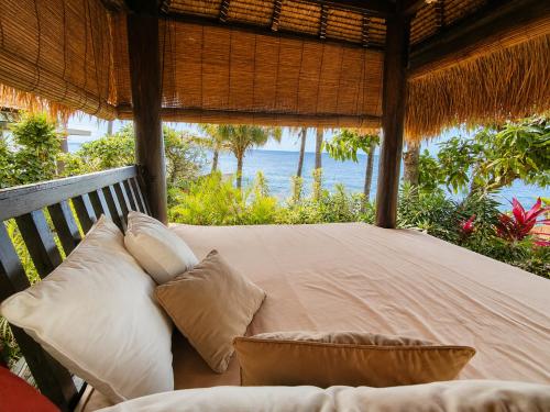 a bed in a room with a view of the ocean at Relax Bali Resort, Diving & SPA, ocean front in Tulamben