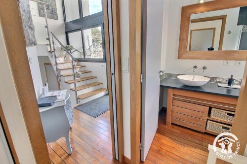 a bathroom with a sink and a mirror and a staircase at Le bigorneau in Trégastel