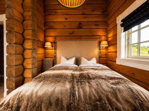 a bedroom with a bed in a log cabin at Dream mountain cabin with jacuzzi and views in Gol