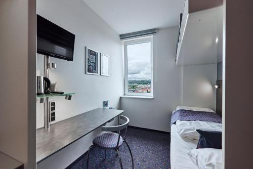 a hotel room with a bed and a desk and a window at Hotel Cabinn Vejle in Vejle