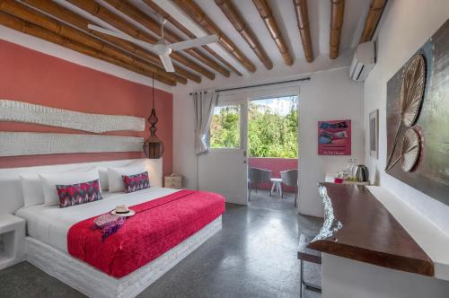 a bedroom with a white bed with a red blanket at PinkCoco Gili Trawangan - Constant Surprises - for Cool Adults Only in Gili Trawangan
