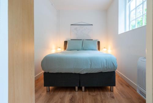 a bedroom with a bed with blue sheets and a window at Zwaluwenburg 4 in 't Harde