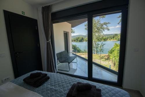 a bedroom with a large window with a view of the water at Vila Dominus Lux in Veliko Gradište