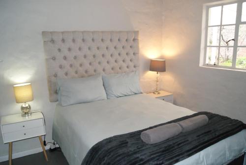 a bedroom with a large white bed and two lamps at Chalet Steenbok in Ladismith