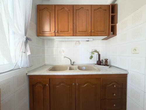 a kitchen with a sink and wooden cabinets at Next to the Beach Apartments , Delta Hospitality in Ofrínion