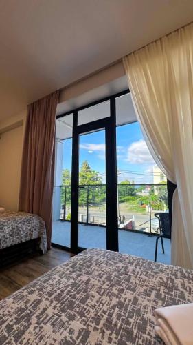 a bedroom with a bed and a large glass window at Hotel Nena in Kobuleti