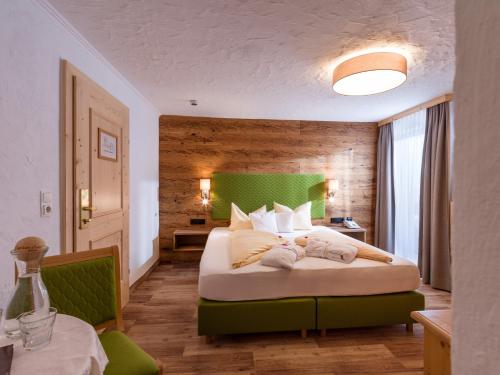 a bedroom with a large bed with a green headboard at Hotel Glockenstuhl in Gerlos