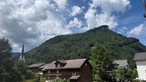 a mountain in the distance with a house and a church at Mellau Appartments 220 in Mellau