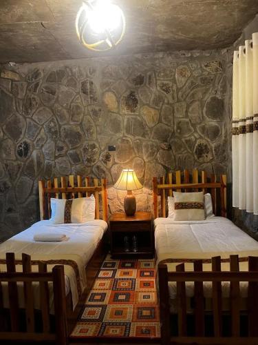 two beds in a room with a stone wall at Belema Resort & Spa in Jemo