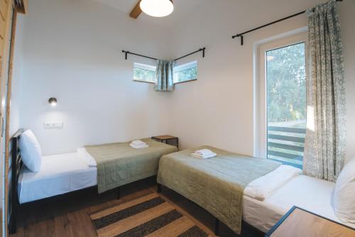 two beds in a room with a window at Olivér cölöpház in Tiszafüred