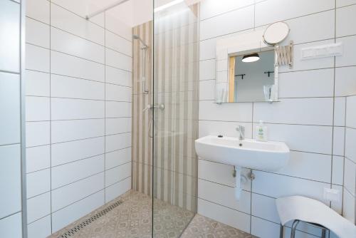 a white bathroom with a sink and a mirror at Olivér cölöpház in Tiszafüred
