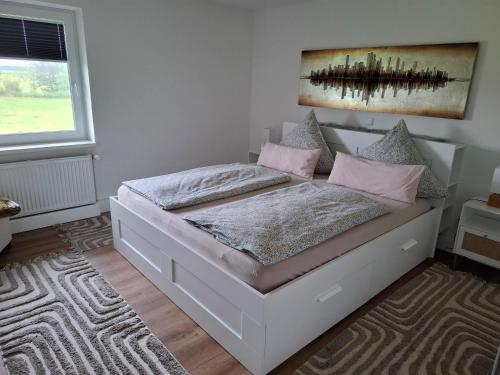a bedroom with a white bed with pink pillows at Ferienwohnung Nordseewind in Aventoft