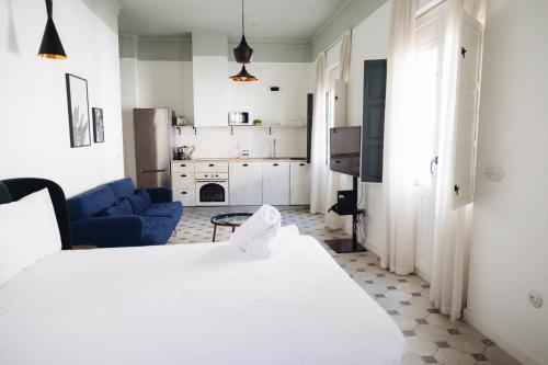 a bedroom with a white bed and a blue couch at Casa Alberola Apartments in Alicante