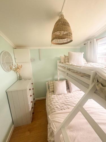 a bedroom with two bunk beds and a window at The Coastal Cosy, St Merryn, Padstow in Saint Merryn