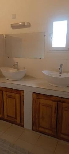 a bathroom with two sinks on a counter with a window at Le Clos Rivière in Ndangane