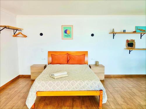 a bedroom with a large bed with orange pillows at A Casa Valentina - Estudio vista panorâmica para o mar in Estreito da Calheta
