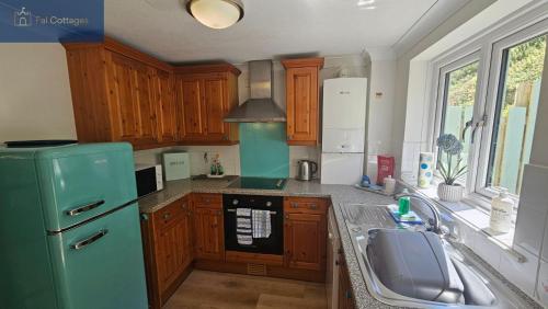 a kitchen with a green refrigerator and a sink at Driftwood in Porthtowan