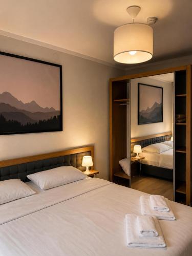 a bedroom with a large white bed and a mirror at Aparthotel Room 107 at Orbi Palace in Bakuriani in Bakuriani