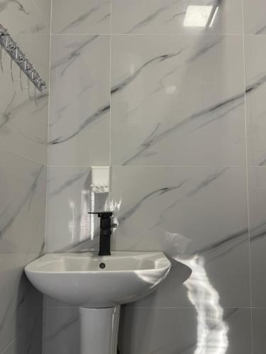 a white sink in a bathroom with marble walls at Bayaman Guest House in Bokonbayevo