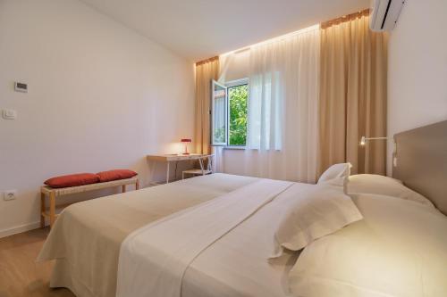 a bedroom with a large white bed and a window at Apartment Na broju3 in Krk