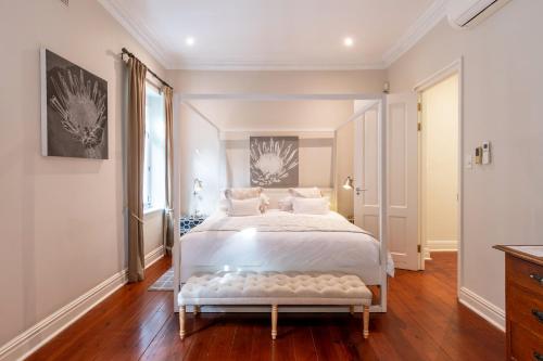 a bedroom with a large white bed with a bench at Purple House Accommodations in Cape Town