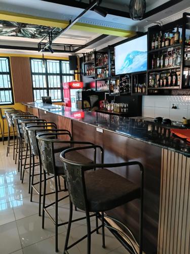 eine Bar mit einer Stuhlreihe und einem Fernseher in der Unterkunft Spass Hotel in Eldoret