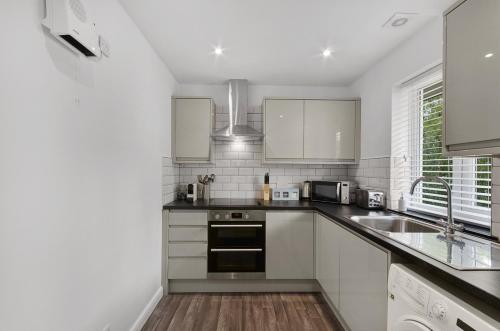 a kitchen with white cabinets and a sink at K Suites - Walsingham Close in Hatfield