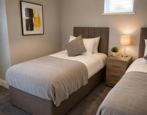 a bedroom with two beds and a table with a lamp at K Suites - Walsingham Close in Hatfield