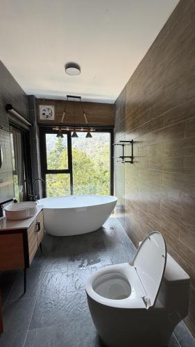 a bathroom with a tub and a toilet and a sink at บ้านเคียงธาร โฮมสเตย์ แม่แมะ Cascade Lodge Homestay in Amphoe Chiang Dao