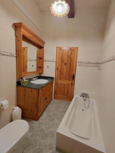 a bathroom with a tub and a sink and a toilet at Il- Pellikan Farmhouse in Għajnsielem