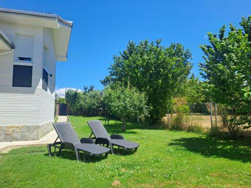 a group of chairs sitting in the grass near a house at Rosales Collection Vacation Villa in Medina de Pomar