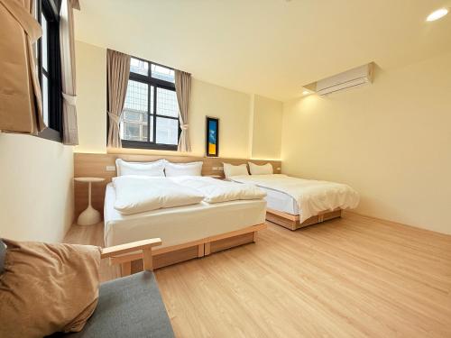a bedroom with two beds and a couch at Jian Guo Hotel in Pingtung City