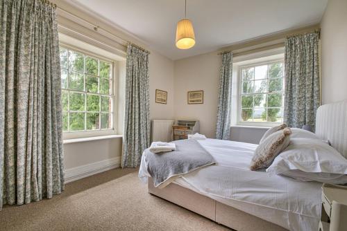 a bedroom with a bed and two windows at Timberley House by Group Retreats in Pulborough