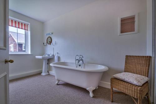 a white bathroom with a tub and a chair at Timberley House by Group Retreats in Pulborough
