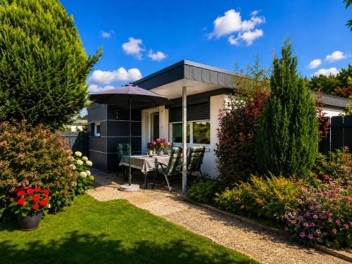 a small house with a table and an umbrella at Schleibungalow Nr15 zw Ostsee und Schlei in Kappeln