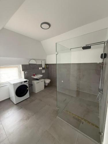 a bathroom with a shower and a washing machine at Deluxe Apartment II in Velpke