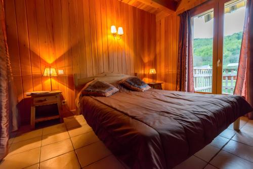 a bedroom with a bed in a room with a window at Chalet Bien-être, Piscine, Spa in La Chapelle-dʼAlagnon