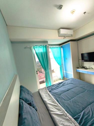 a bedroom with a bed and a window with blue curtains at Studio Apartemen Parahyangan Residence by Anton in Bandung